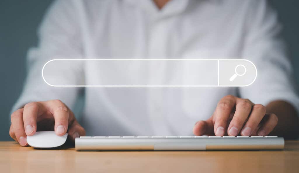 Junger Mann im Hemd arbeitet mit Maus und Tastatur an einer Landingpage