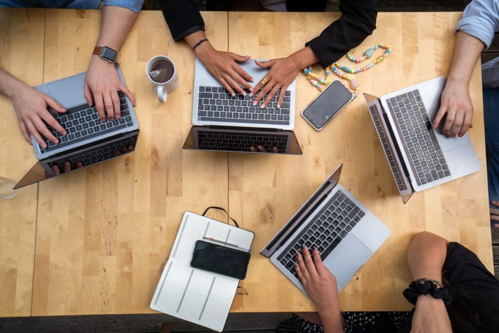 Personen arbeiten an Webdesign auf Computer von oben fotografiert